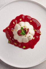 Vertical orientation panna cotta with raspberry syrup, pistachios, berries and mint, high key, top...
