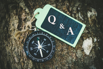 Q & A  text written on wooden tag with magnetic compass and magnifying glass on old wooden background. A concept.