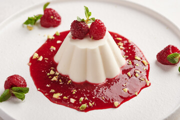 Panna cotta with raspberry syrup, pistachios, berries and mint, high key, close up