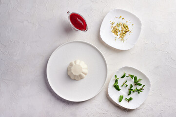 Ingredients for panna cotta with raspberry syrup, pistachios, berries and mint, high key, top view, copy space
