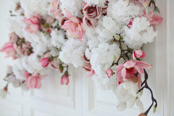 Floral spring decor of artificial flowers on a white wall close-up. Design and decoration concept