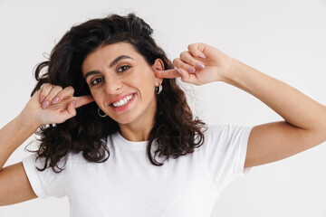 Cheerful young brunette woman covers ears isolated