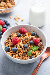 Delicious granola with berries in bowl served with bottle of almond milk. Healthy vegan breakfast food