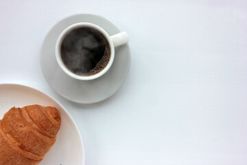 Cup of coffee and croissant on white background. Top view, copy space. Morning espresso on table. Healthy breakfast.