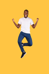 Fototapeta na wymiar Excited African Man Jumping Shaking Fists Celebrating Success, Yellow Background