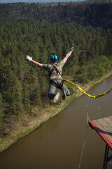 Man ropejumper jumps into the abyss with a safety rope from a great height above the river and the...
