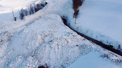 Road leads through an avalanche of snow. The avalanche was removed with large machines so that the road is passable again. It is still a great danger to drive through the road.