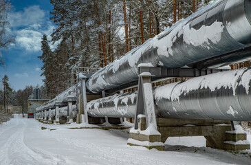 Huge industrial pipelines of central heating system. Snow on pipes.