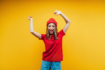 Dancing girl on a yellow background. Drive photo in the studio. Stylishly dressed in red girl...