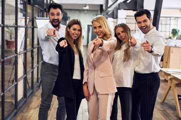 Group of young business people are working together in modern office pointing to the camera. Successful team in coworking. Freelancers.