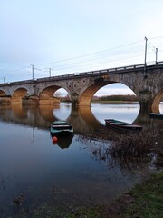 Paysage de rivière calme avec un pont de chemin de fer et deux barques sur la Maine
