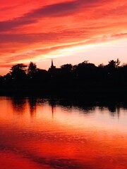 Red sunset over the river Maine with the silhouette of a church tower reflected in the water