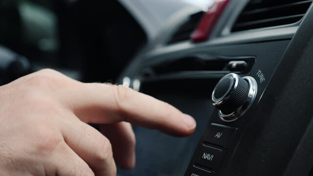 Male hand tunes the radio in the car