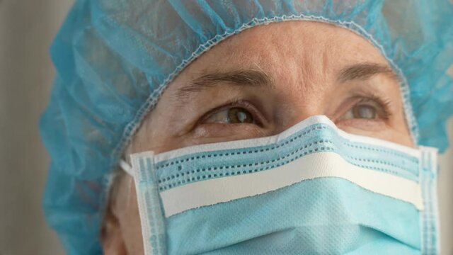 Sad and tired medic opens eyes and looking atraight at camera. Medical nurse portrait closeup. Concept exhausted health care worker.