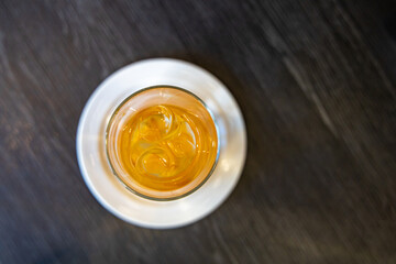 Carafe of water with orange slices on the brown table.