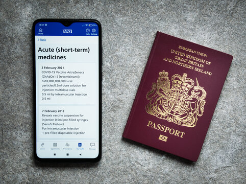 The UK's NHS smartphone app shows proof of an Oxford AstraZeneca COVID vaccination given given on 2nd February 2021. A UK passport appears on the right.