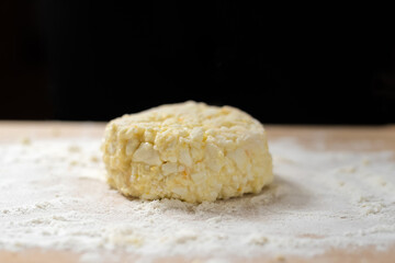 Cottage cheese pancakes on a wooden board with flour close up in the background black background with copy space