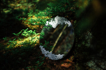 Round mirror with lace with reflection of pine branches in the forest