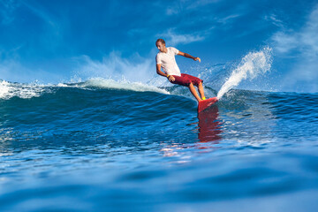 Male surfer on a blue wave at sunny day