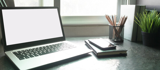 Laptop computer with white blank screen on desk in workspace and copy space concept