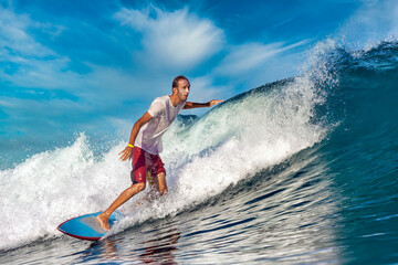 Male surfer on a blue wave at sunny day