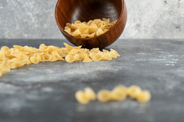 Raw dry farfalle tonde macaroni on a marble background