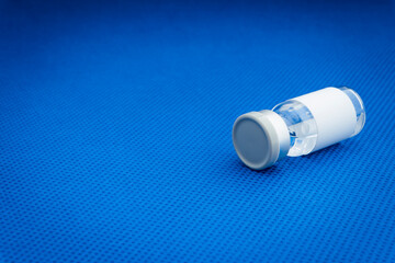 Vial vaccine bottle on blue background. Vaccination and copy space concept