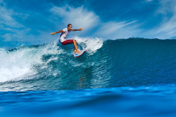 Male surfer on a blue wave at sunny day