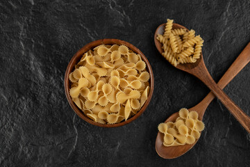 A wooden bowl full of raw farfalle tonde macaroni