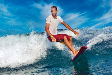 Male surfer on a blue wave at sunny day