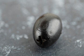 One black olive fruit on a marble background