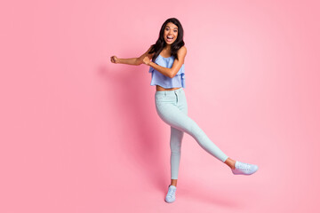 Fototapeta na wymiar Full size photo of optimistic brunette lady dance wear blue top trousers sneakers isolated on pink color background