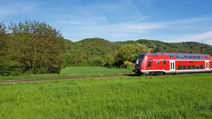 Red train Was running through a green meadow. On a bright day.