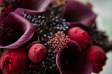 a beautiful and expensive bouquet with red roses and purple calla lilies and dark blue berries....