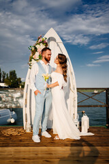 wedding ceremony by water on dock. bride and groom.