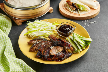 Peking duck chinese food. Yellow plate with vegetables and sauce on dark slate table. Chinese, asian, authentic food concept