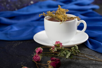 A cup of tea with dried flowers on a black background