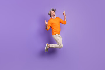 Fototapeta na wymiar Full size photo of young crazy funky funny smiling old man jumping showing rock'n'roll sign isolated on violet color background