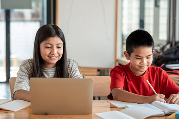 Front view of Asian brothers and sisters, studying online together at home