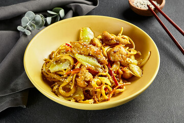 Curry Udon Noodles. Asian curry udon in yellow plate with wooden chopstick on dark slate table....