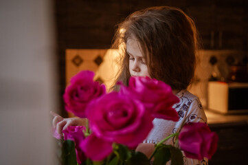 Cute little girl with long hair with a bouquet of red roses. Holiday concept. International Women's Day