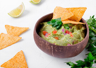 Guacamole dip in a wooden bowl and nacho chips. Mexican food