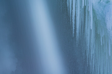 Winter landscape of a cascade captured with motion blur and framed by blue ice, Comstock Creek, Michigan, USA