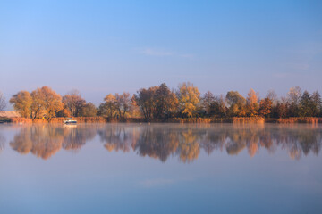 drzewa odbijające się w jeziorze, jesienny poranek