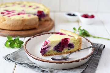 A delicious piece of berry pie on a beautiful white plate on a white table. Raspberry pie on a wooden table