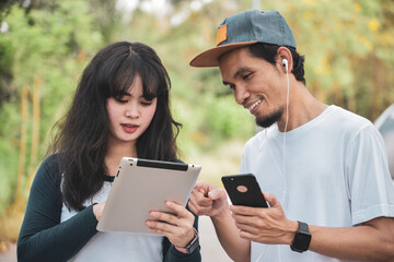 Young Asian couple happily chatting with their friends on social networks with tablet.