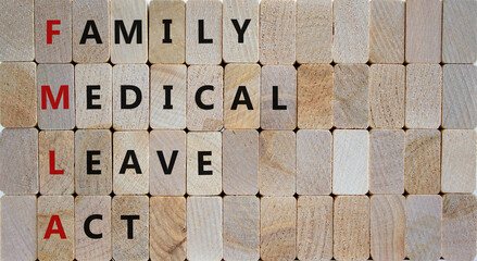 FMLA, family medical leave act symbol. Concept words FMLA, family medical leave act on wooden blocks on a beautiful wooden background. Copy space. Medical and FMLA, family medical leave act concept.