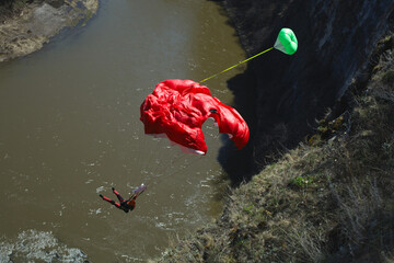 Basejumper opens the parachute at a low altitude after jumping from a high cliff above the river. Basejumping.