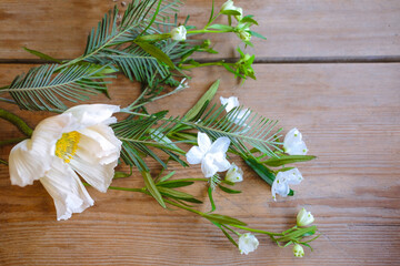 Spring white flowers with green leaves on a wooden table