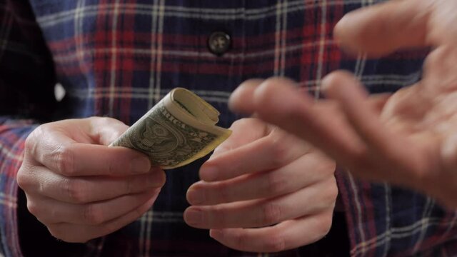Close-up of a woman's hand giving money bills to another person.